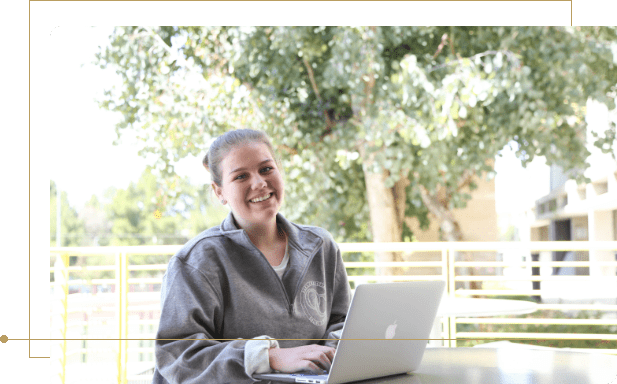 Smiling girl working on computer and taking online course outdoors.